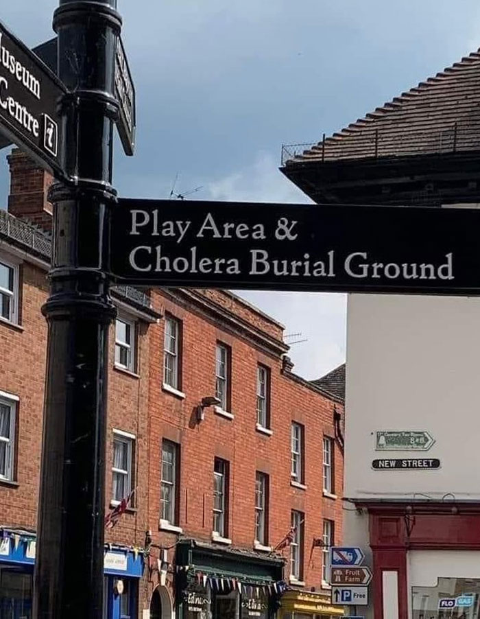 Street sign showing a play area located next to a cholera burial ground illustrating design and architecture nightmares.