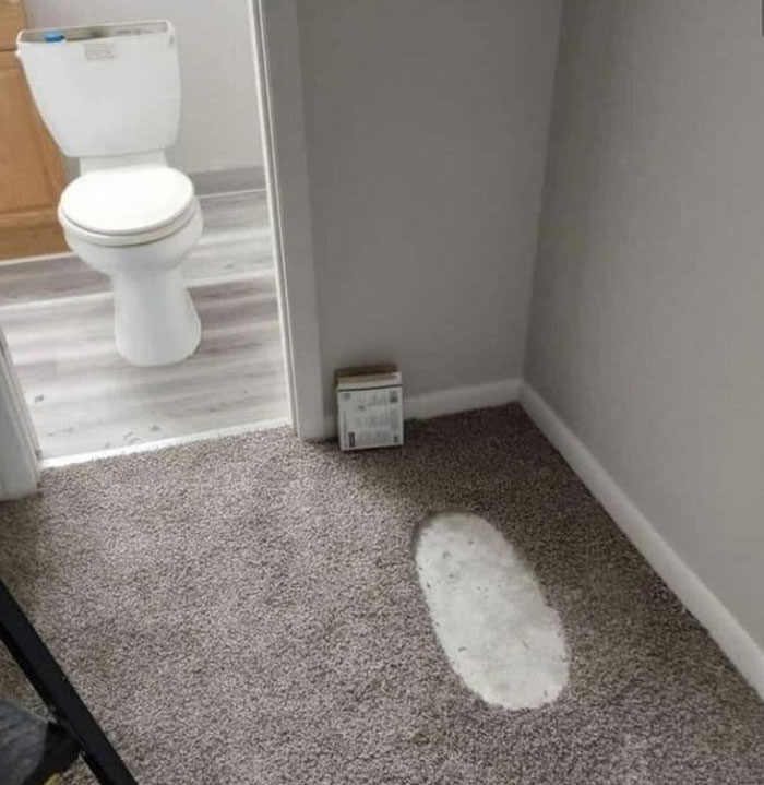 Carpet installation fail near bathroom door showing a cutout patch exposing concrete floor, a design and architecture nightmare.