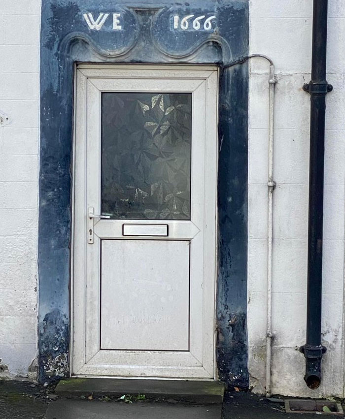 White door with frosted glass set in an uneven frame dated 1666, showcasing a design and architecture nightmare example.