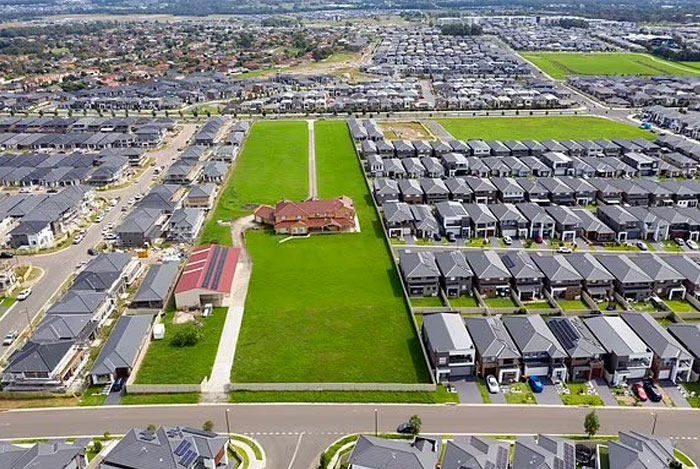 Aerial view of a large house surrounded by uniform suburban homes showing design and architecture nightmares.