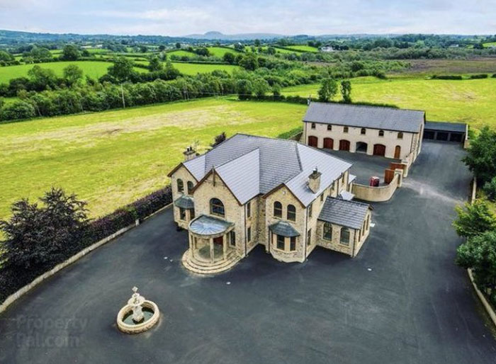 Large stone house with attached garage surrounded by vast green fields, illustrating design and architecture nightmares.