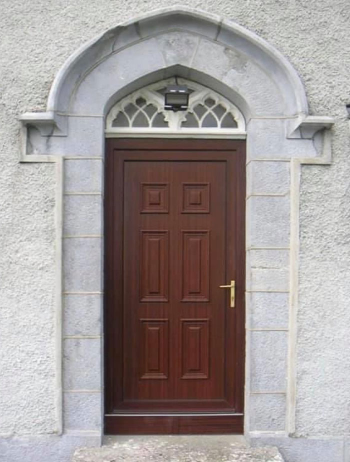 Wooden door with a security camera blocking the entrance, a design and architecture nightmare showing lack of common sense.
