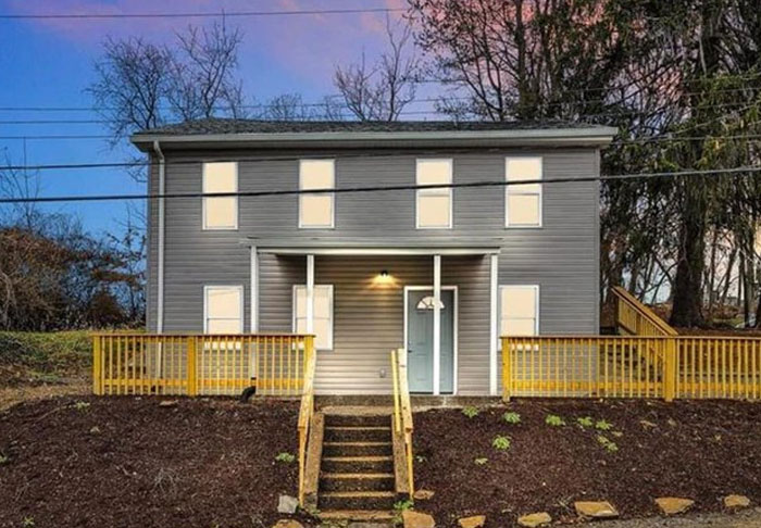 Two-story house with poorly placed front steps and railing, showcasing a design and architecture nightmare.