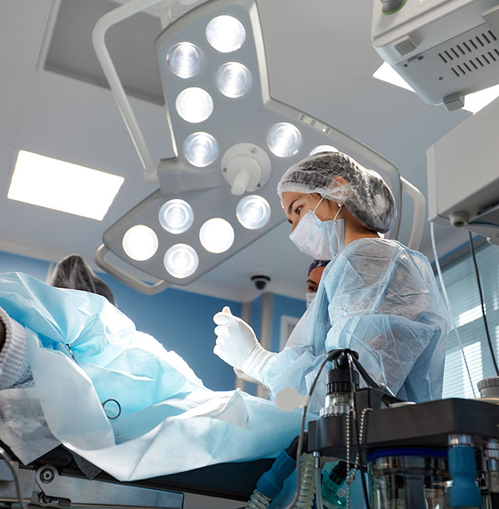 Surgeon in operating room performing plastic surgery procedure under bright surgical lights in 2025 medical setting.