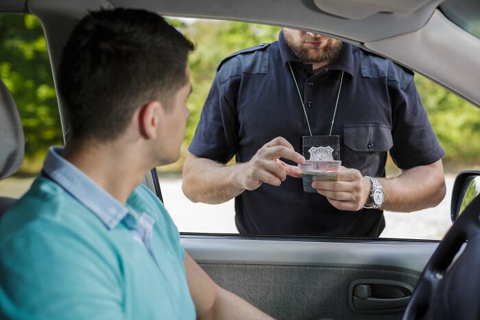 Police officer checking driver’s ID after a traffic stop, illustrating dumb drivers instantly getting what they deserved.