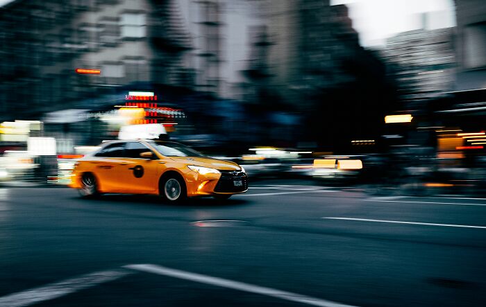 Yellow taxi speeding through a city street at night, illustrating stories of dumb drivers instantly getting what they deserved.