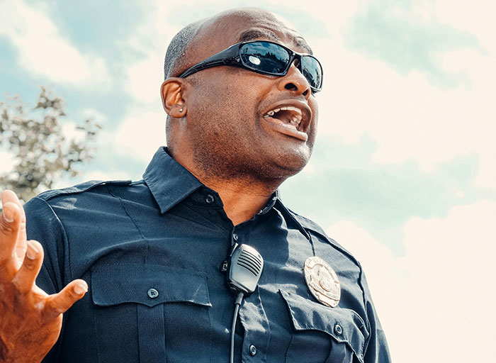 Police officer wearing sunglasses and uniform reacting to a situation involving dumb drivers instantly getting consequences.