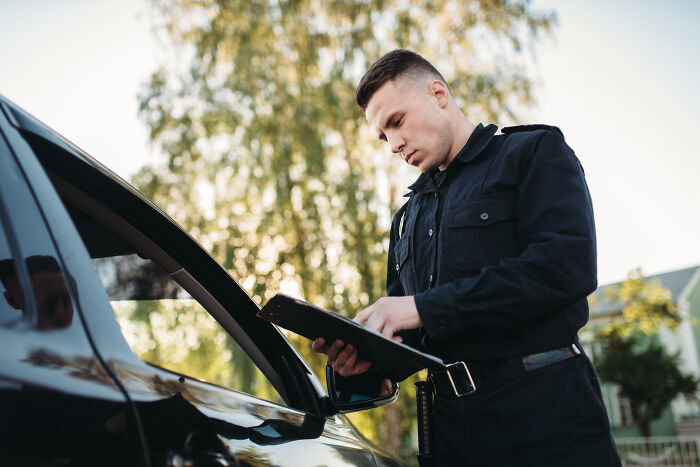 Police officer writing a ticket for a driver, illustrating stories of dumb drivers instantly getting what they deserved.