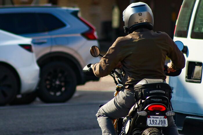 Motorcyclist wearing helmet riding through traffic highlighting dumb drivers instantly getting consequences.
