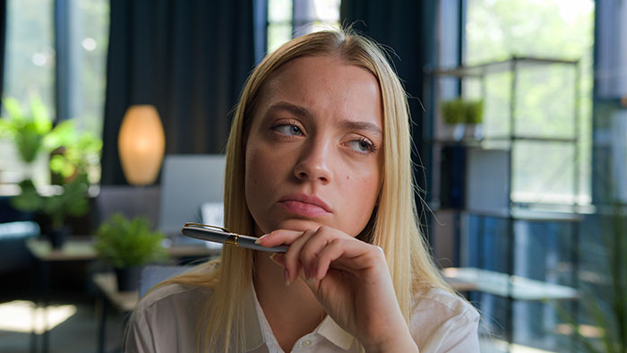 Young woman looking thoughtful and disappointed indoors, reflecting on boyfriend upgrade after lack of calls or visits post surgery.