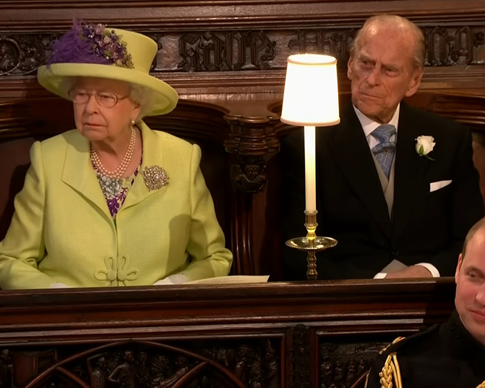 Queen Elizabeth II and Prince Philip seated in a church setting before Prince Harry and Meghan Markle wedding ceremony.