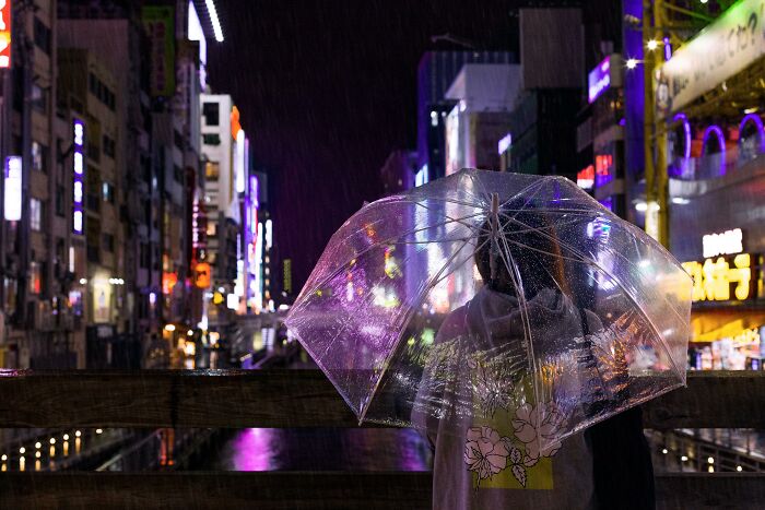 Couple sharing a transparent umbrella at night in a city, illustrating relationship gestures and princess treatment themes.
