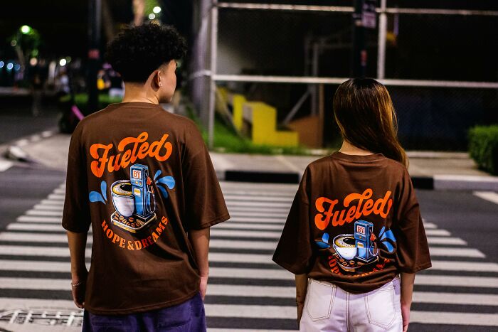 Two people wearing matching graphic shirts standing on a street at night, illustrating relationship gestures concept.
