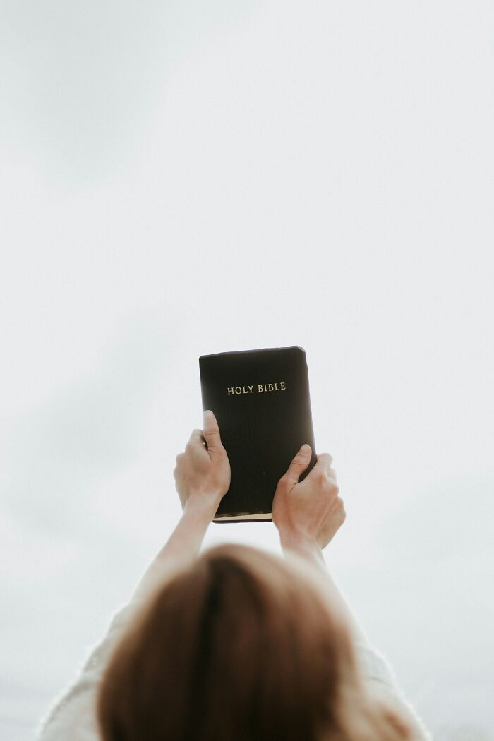 Person holding up a Holy Bible against a bright sky, illustrating culture shocks people experience while visiting Australia.