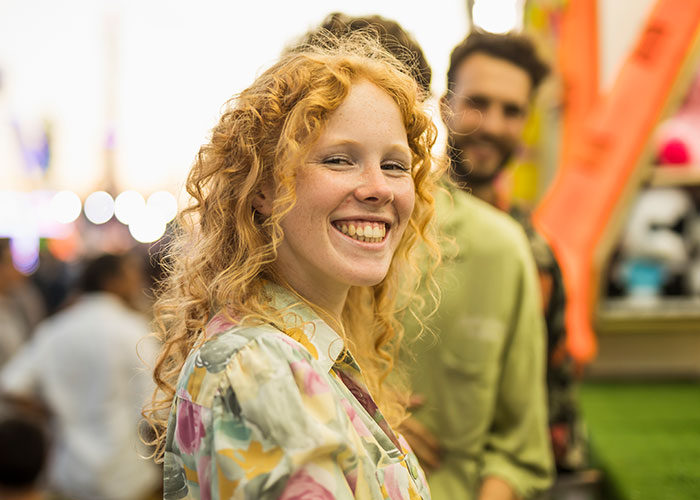 Young woman smiling confidently in a crowd, illustrating psychological tricks people use on themselves and others effectively.