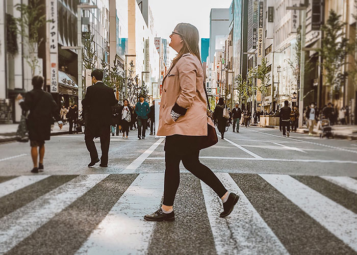 Woman crossing busy city street, illustrating psychological tricks people use on themselves and others because they work.