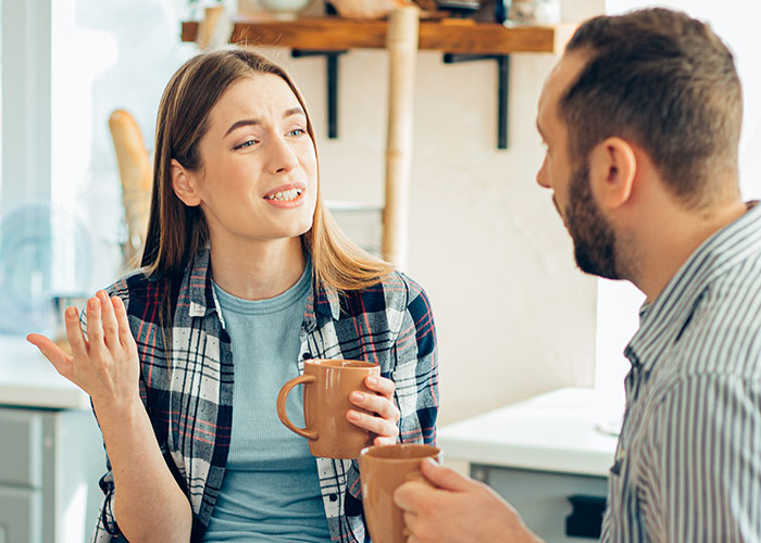 A woman and man having a conversation while holding mugs, illustrating psychological tricks people use on themselves and others.