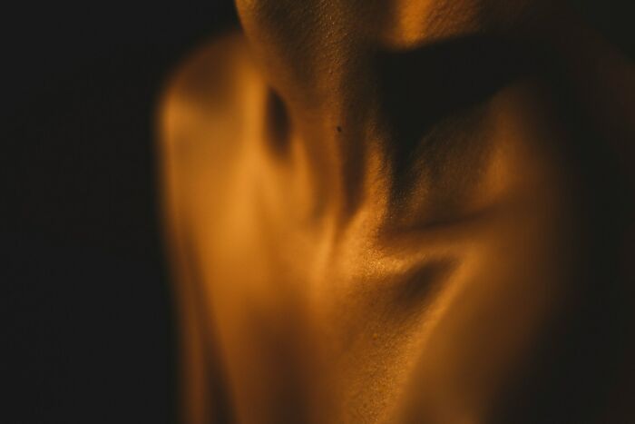 Close-up of a human neck and shoulder bathed in warm light, illustrating comically absurd facts about the human body.