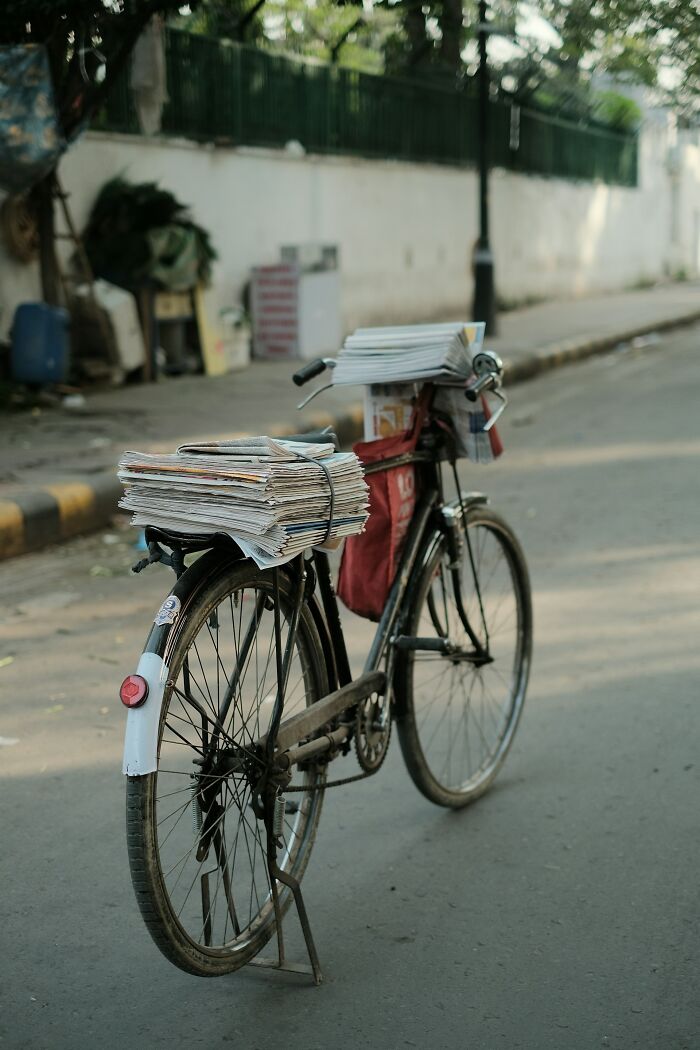 Bicycle loaded with stacks of newspapers parked on a quiet street, illustrating internet rabbit holes that took over lives.
