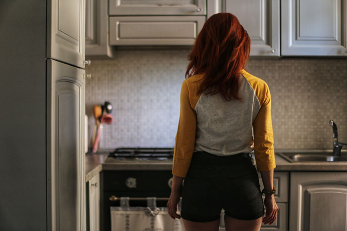 Woman with red hair standing in a kitchen, capturing a moment reflecting parents and children sharing brutally honest reasons parents were unhappy.