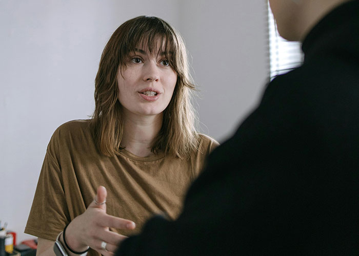Young woman refusing to quit job after husband&rsquo;s promotion, engaged in serious discussion about gender roles.