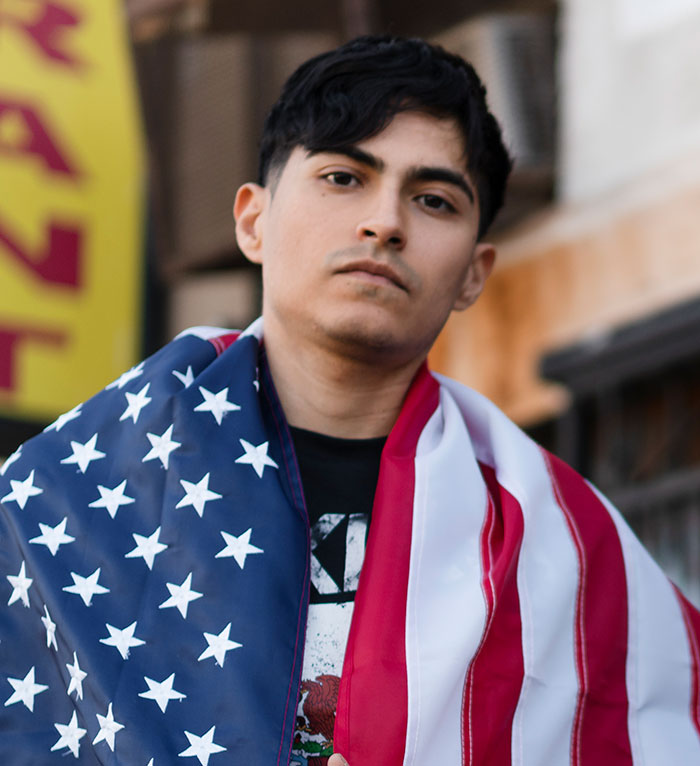 Young man wrapped in an American flag looking serious, illustrating stories of people's lies getting out of hand and changing lives.