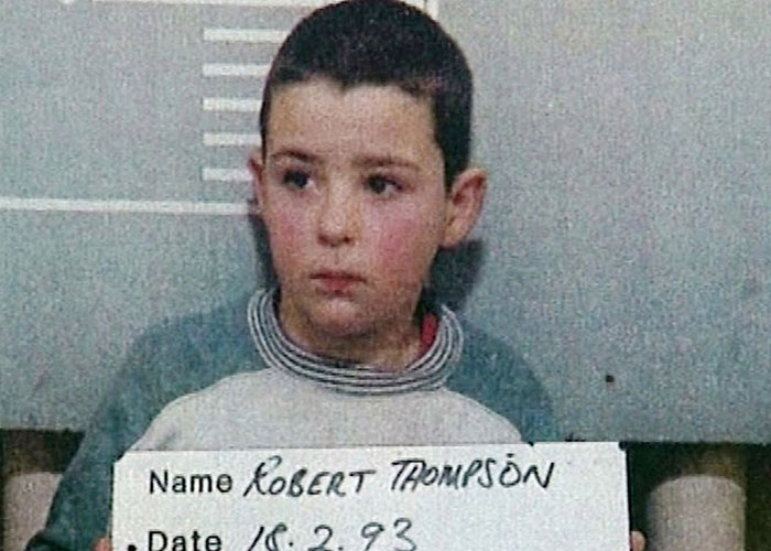 Young boy holding a sign in a police mugshot, representing child criminals involved in disturbing acts.
