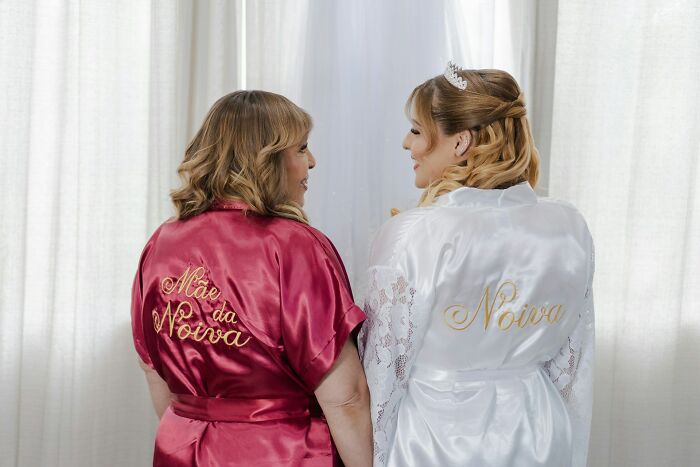 Two women in satin robes sharing a moment, highlighting work secrets behind personal care professions.