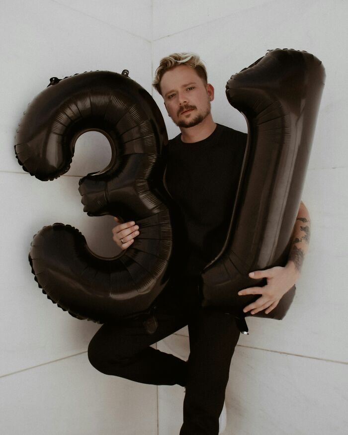 Man holding large black balloons shaped as numbers 3 and 1, illustrating returning MIL&rsquo;s $1,200 weird decor debate.