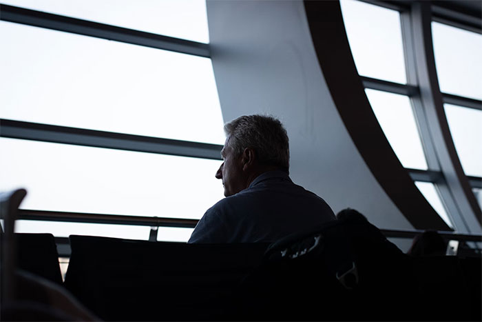 Man sitting alone in a modern waiting area, reflecting on a long-awaited proposal after 30 years and four kids. Man sitting alone in a modern waiting area, reflecting on a long-awaited proposal after 30 years and four kids.