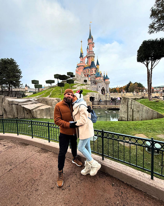 Couple posing near a castle at a theme park, unrelated to crypto scammer behind $500M scheme or Dubai incident.