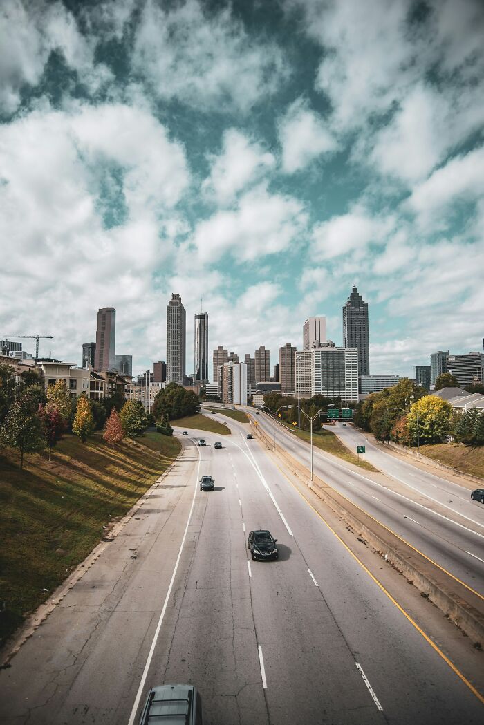 Highway leading to a downtown skyline under a cloudy sky, highlighting urban life in Miami cityscape.