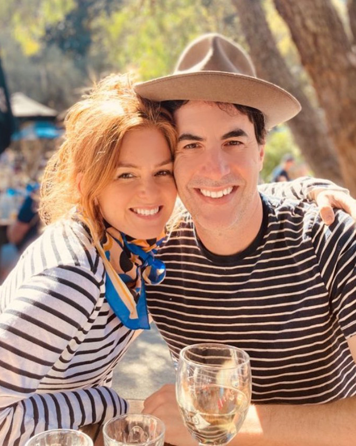 Isla Fisher smiling with a man outdoors, highlighting emotional struggle after difficult divorce with Sacha Baron Cohen.