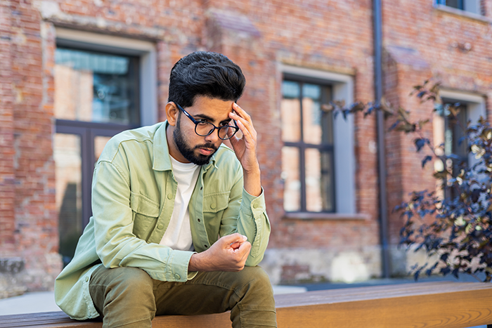Young man looking stressed and thoughtful outdoors after failing lady's unexpected loyalty test in longtime friendship.