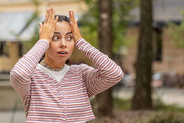 Woman in striped sweater looking worried and surprised, as fiance detective treats partner suspicious behavior outside.