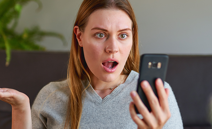 Shocked woman reading phone message about partner cheating during pregnancy and postpartum, expressing disbelief at betrayal.