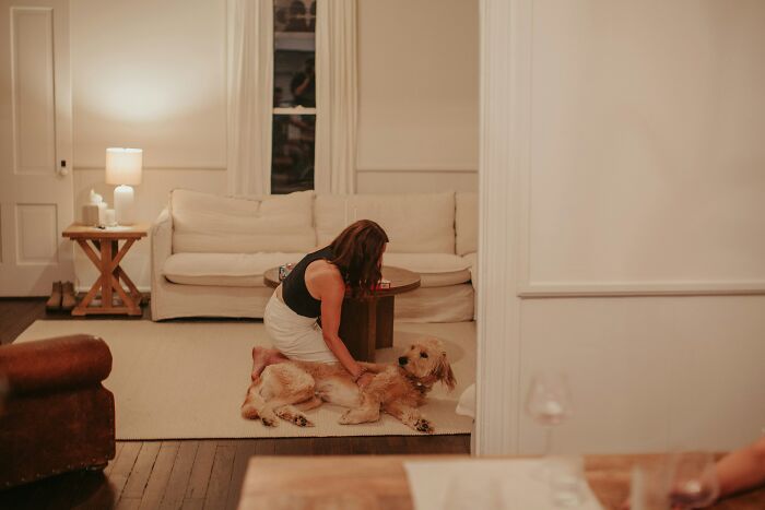 Woman kneeling and comforting her dog indoors, reflecting the situation of rehoming a dog after abandonment abroad. Woman kneeling and comforting her dog indoors, reflecting the situation of rehoming a dog after abandonment abroad.