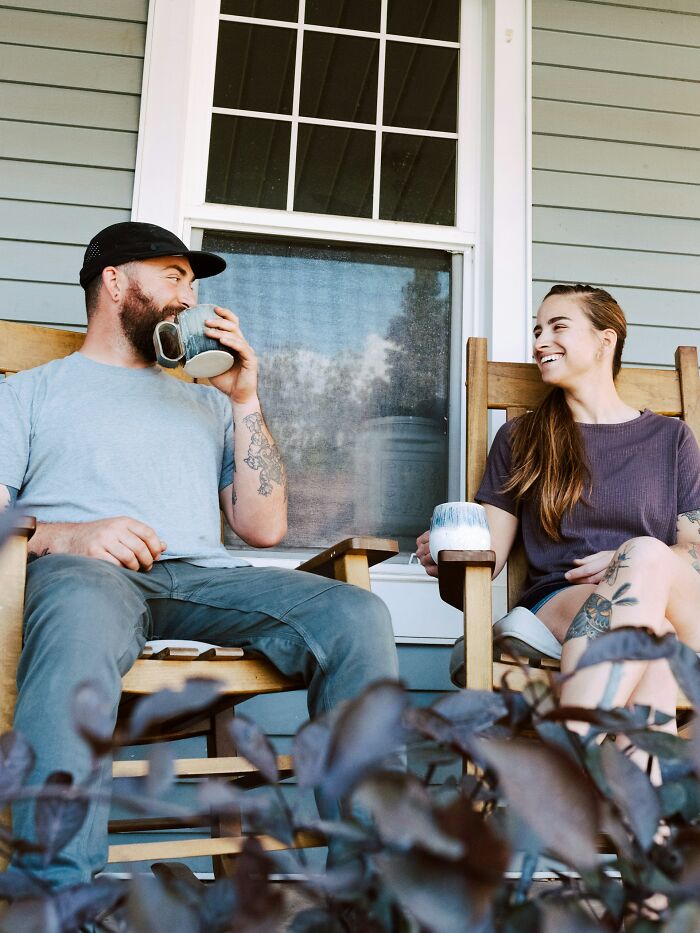 Two people sitting on a porch drinking coffee and smiling, illustrating culture shocks people experience while visiting Australia.
