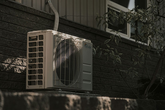 Outdoor air conditioning unit mounted on a brick wall with shadows, representing some of the scariest things people have woken up to.