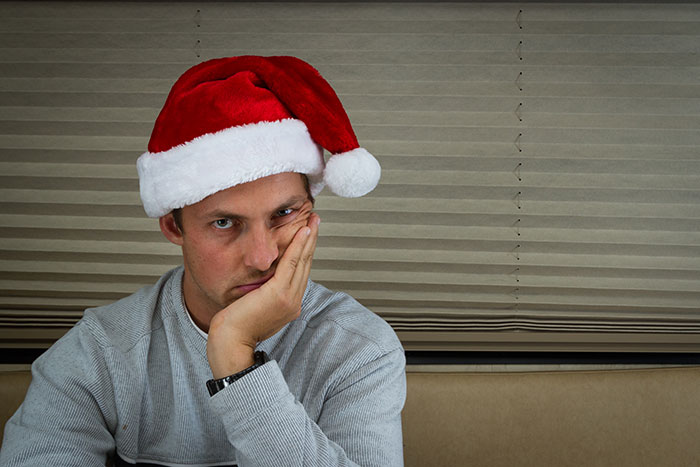 Man wearing Santa hat looking frustrated, representing secret Santa organizer enforcing gift participation rules.