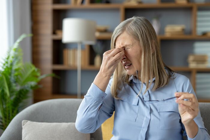 Woman in blue shirt at home showing frustration after falling for scams and dealing with emotional impact.