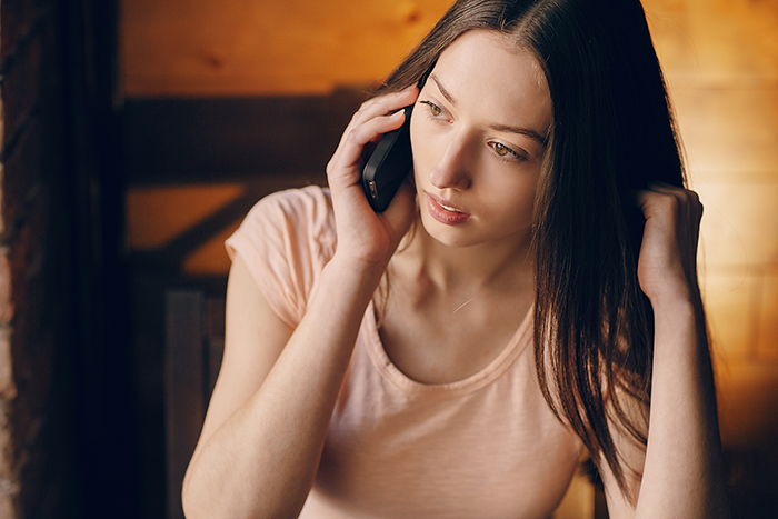 Young woman looking concerned while talking on the phone, reflecting sibling neglect and desire to reconnect after years apart