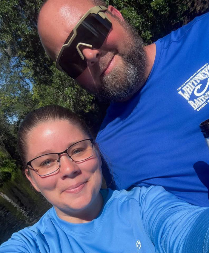 Two people outdoors wearing blue shirts and sunglasses, unrelated to stepsibling investigation after teen's body found on Carnival cruise.
