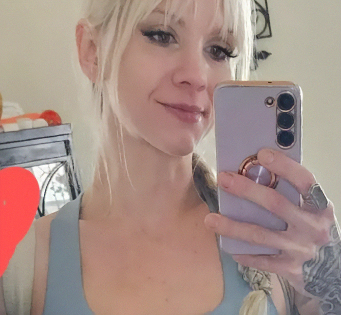 Young woman taking a selfie with smartphone, linked to viral mom who called autistic boy the n-word facing trial.