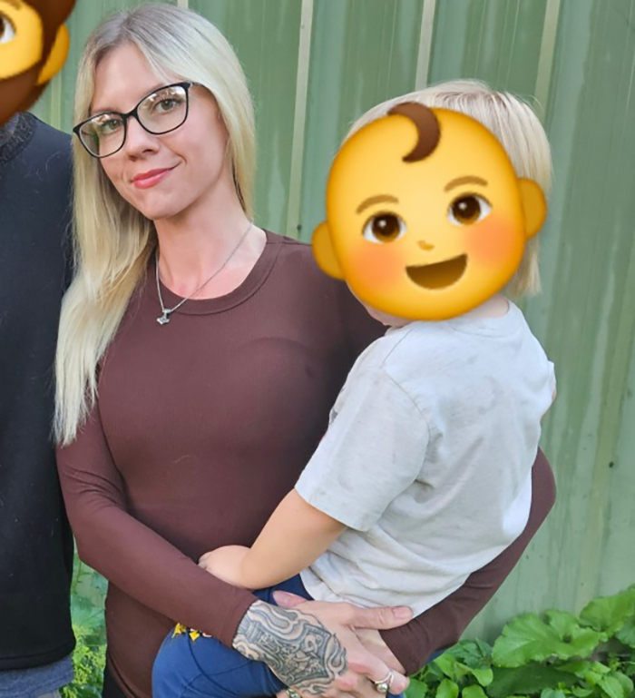 Woman with tattooed hand holding young child with covered face outdoors, related to viral autistic boy playground clash trial