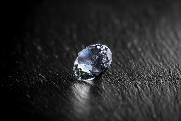 A sparkling gemstone resting on a textured dark surface, symbolizing rare and craziest coincidences experienced by people.