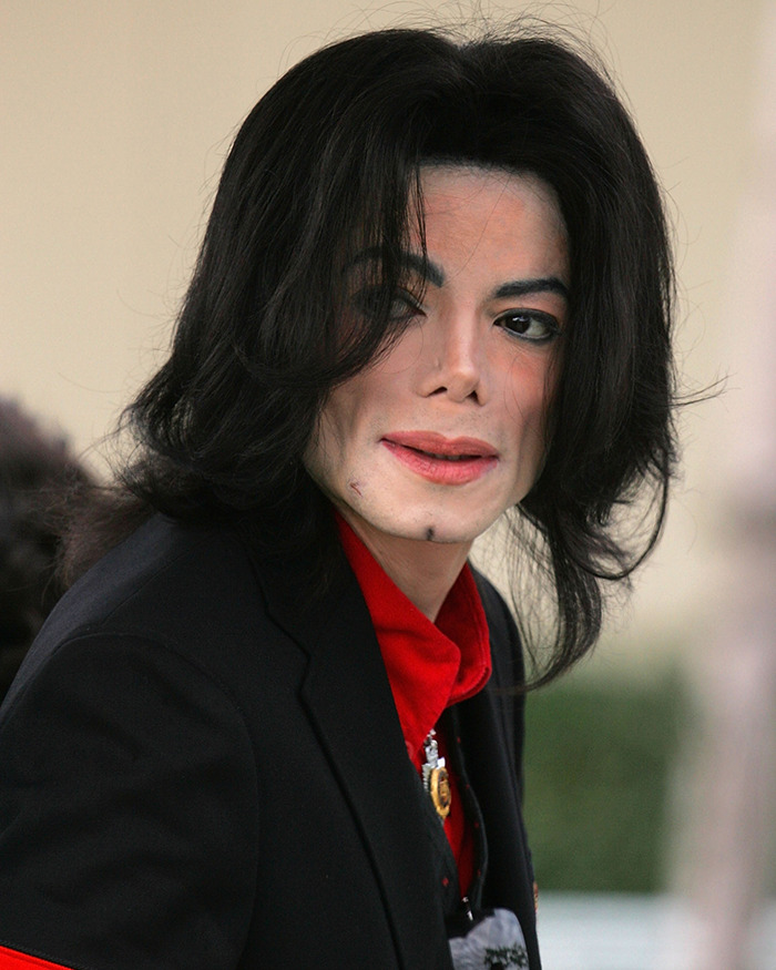 Michael Jackson in a black jacket and red shirt, captured during public appearance amid disturbing new allegations.