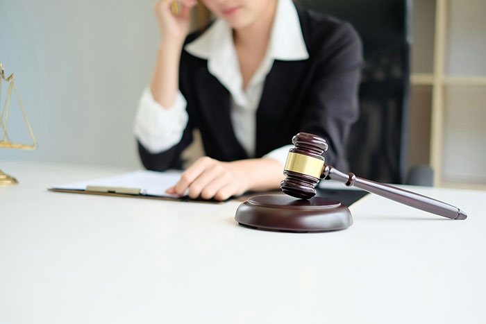 Person in business attire at desk with gavel, representing judgment and decision-making in the college experience.