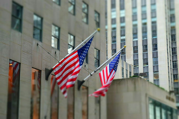 American flags waving outside tall buildings, representing a common scene in the college experience in the USA.