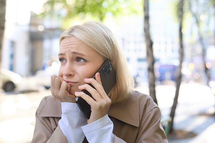 Woman looking disappointed while talking on phone outdoors, illustrating free babysitting expectations and family conflict.